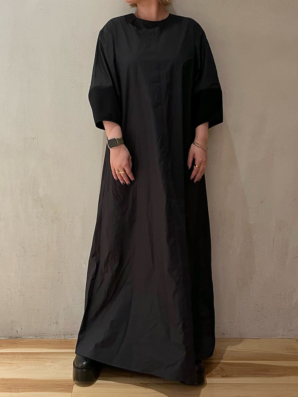 ブラック系のワンピース、ブラック系のブーツを着用したレディースの春コーディネートの2枚目の写真