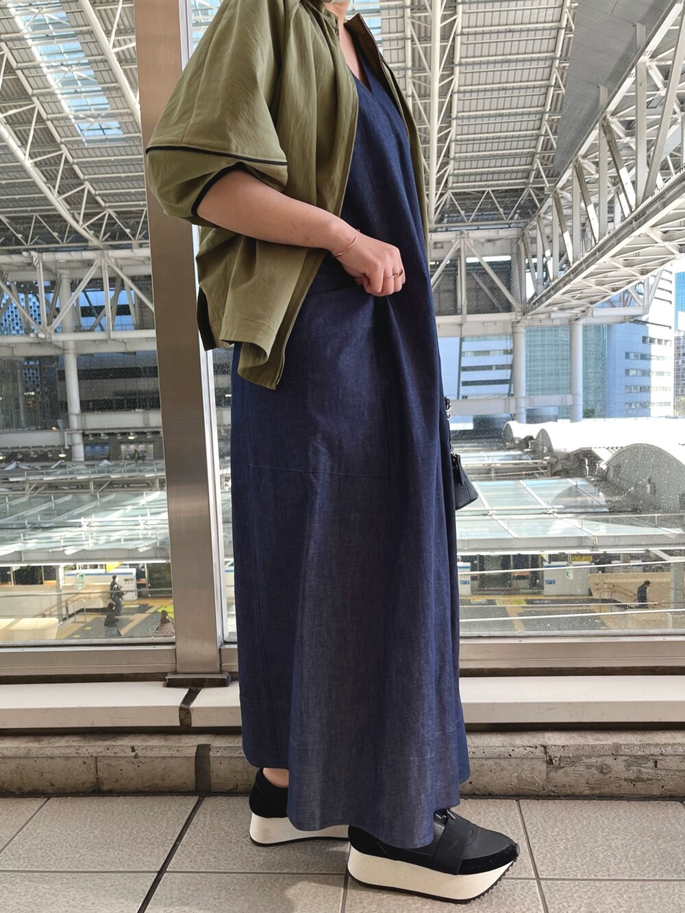 グリーン系のブルゾン、ブルー系のワンピース、ブラック系のスニーカーを着用したレディースの春コーディネートの6枚目の写真