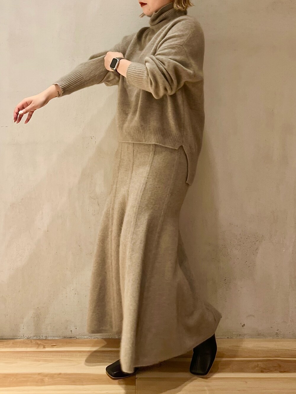 ベージュ系のニット/セーター、ベージュ系のスカート、ブラック系のブーツを着用したレディースの秋コーディネートの2枚目の写真