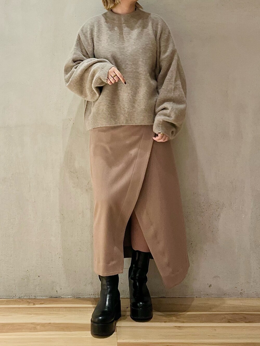 ベージュ系のニット/セーター、ベージュ系のスカート、ブラック系のブーツを着用したレディースの秋コーディネートの2枚目の写真