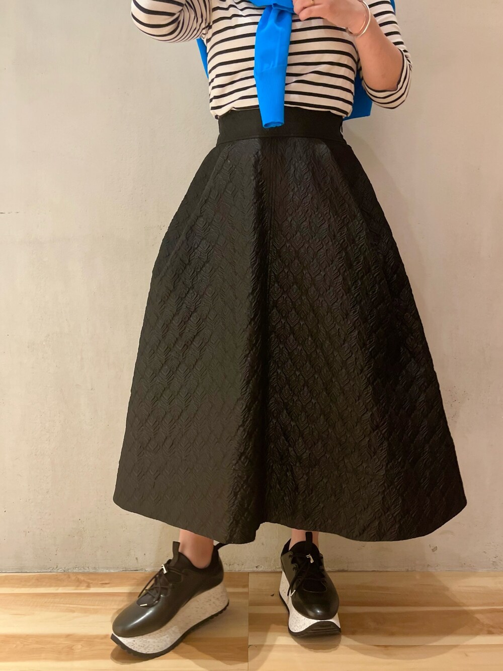 ブルー系のカーディガン/ボレロ、ブラック系のスカート、ブラック系のスニーカーを着用したレディースの春コーディネートの5枚目の写真