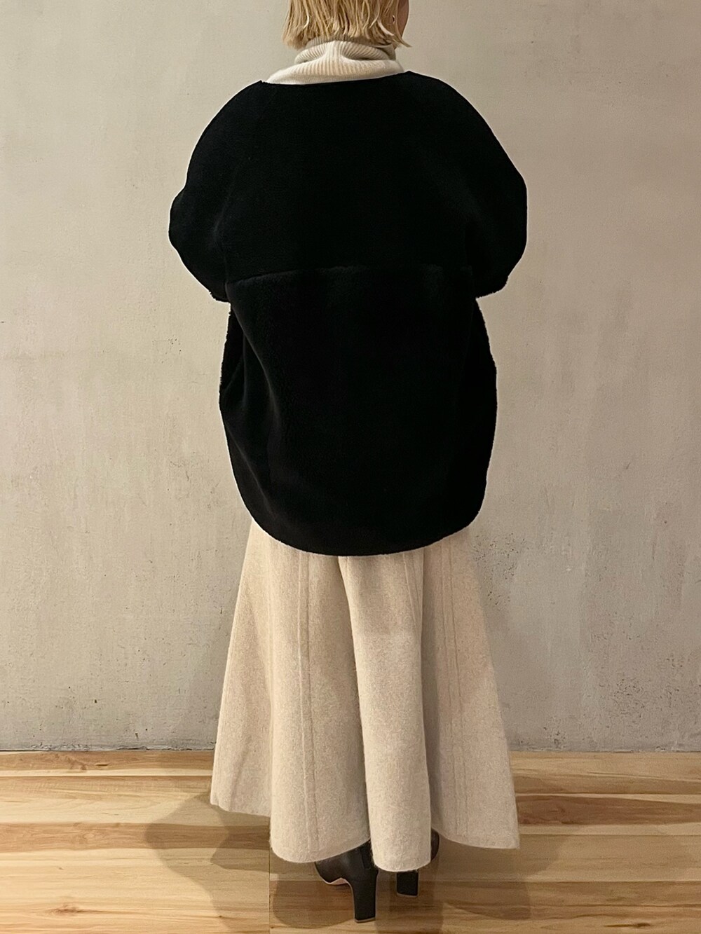 ブラック系のノーカラーコート、ホワイト系のニット/セーター、ホワイト系のスカートを着用したレディースの秋コーディネートの4枚目の写真