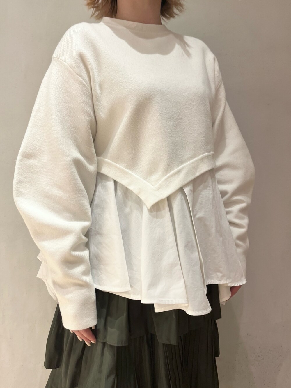 ホワイト系のニット/セーター、ベージュ系のスカート、ブルー系のスニーカーを着用したレディースの秋コーディネートの5枚目の写真