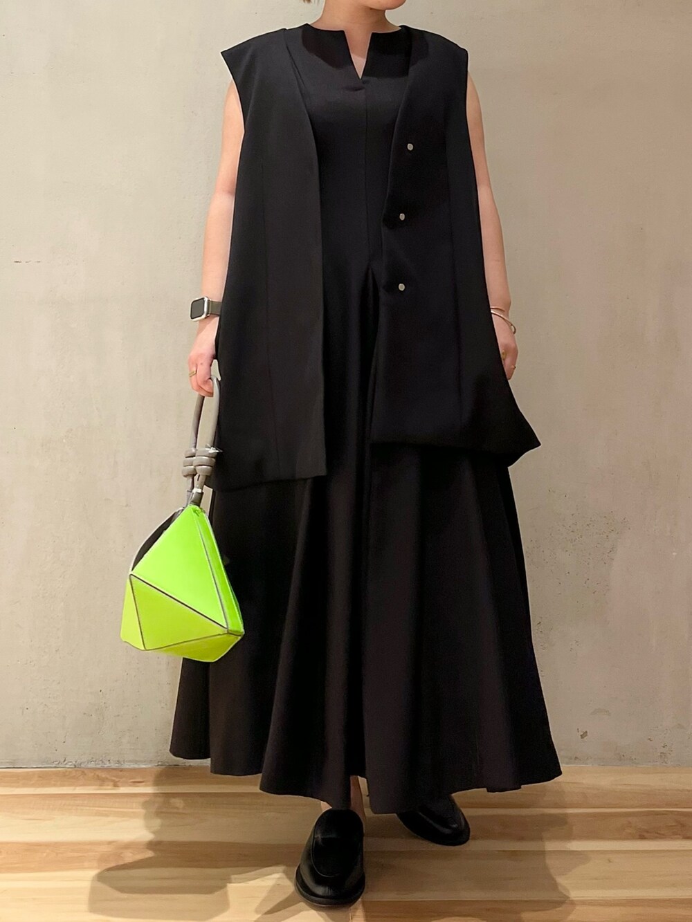 ブラック系のテーラードジャケット、ブラック系のワンピース、グリーン系のハンドバッグを着用したレディースの冬コーディネートの3枚目の写真