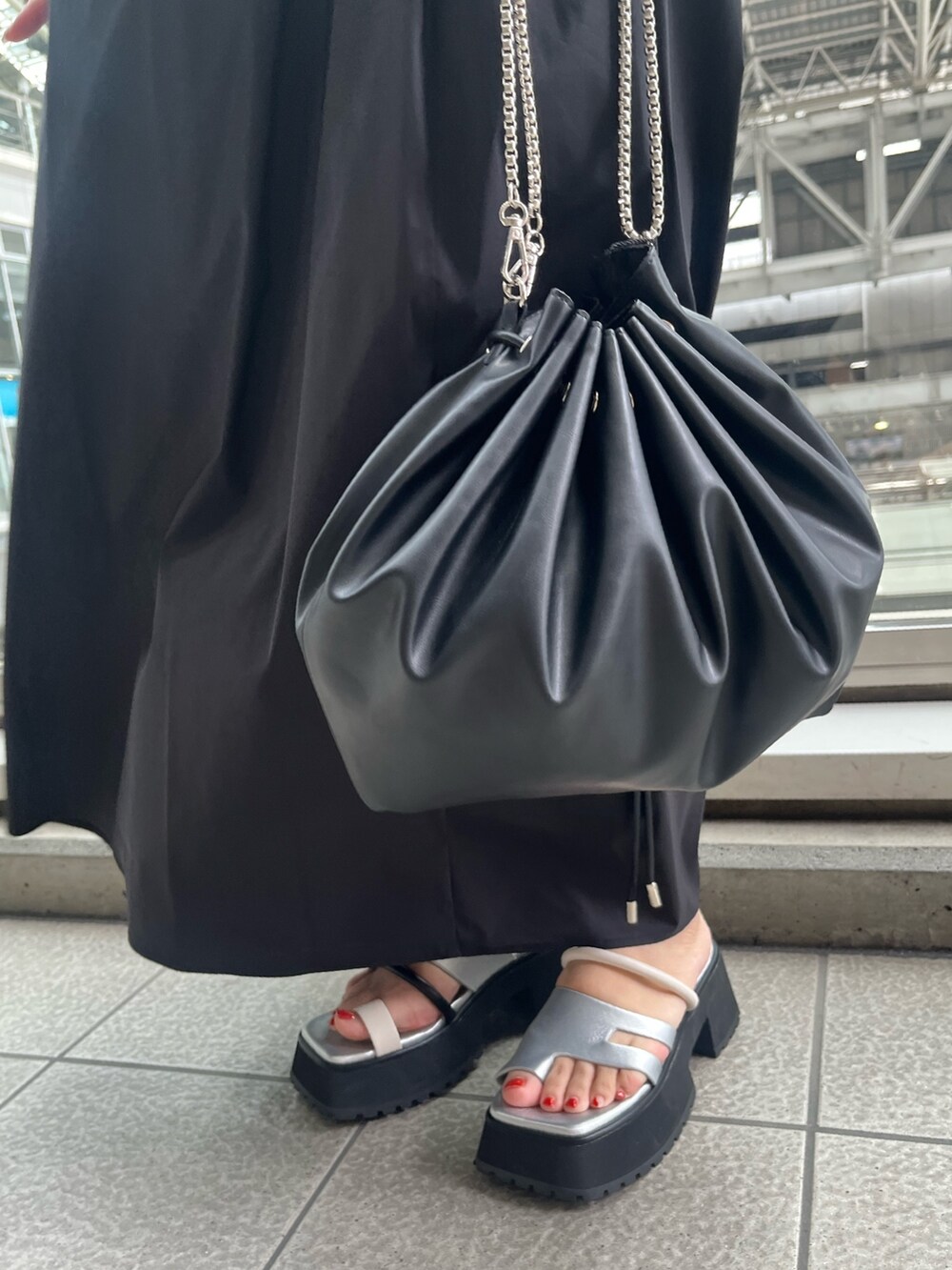 ブラック系のワンピース、ブラック系のショルダーバッグ、その他のサンダルを着用したレディースの春コーディネートの6枚目の写真