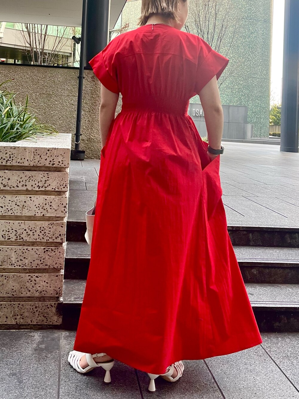 レッド系のワンピース、ホワイト系のハンドバッグ、ホワイト系のサンダルを着用したレディースの冬コーディネートの3枚目の写真