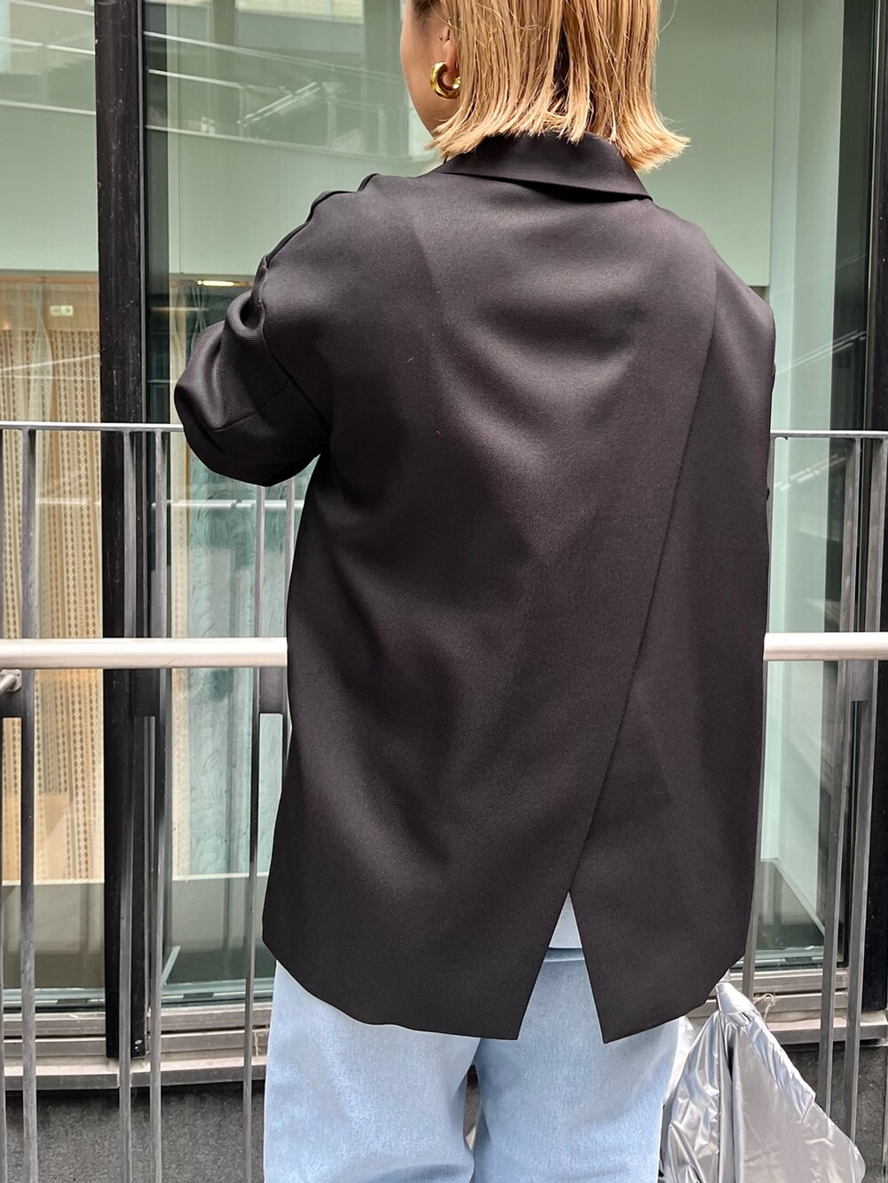 ブラック系のテーラードジャケット、イエロー系のニット/セーター、ブルー系のデニムパンツを着用したレディースの冬コーディネートの7枚目の写真