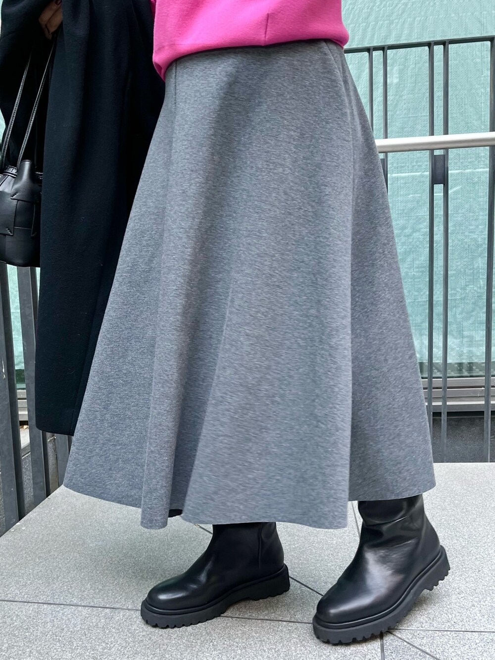 ピンク系のニット/セーター、ブラック系のチェスターコート、グレー系のスカートを着用したレディースの冬コーディネートの10枚目の写真