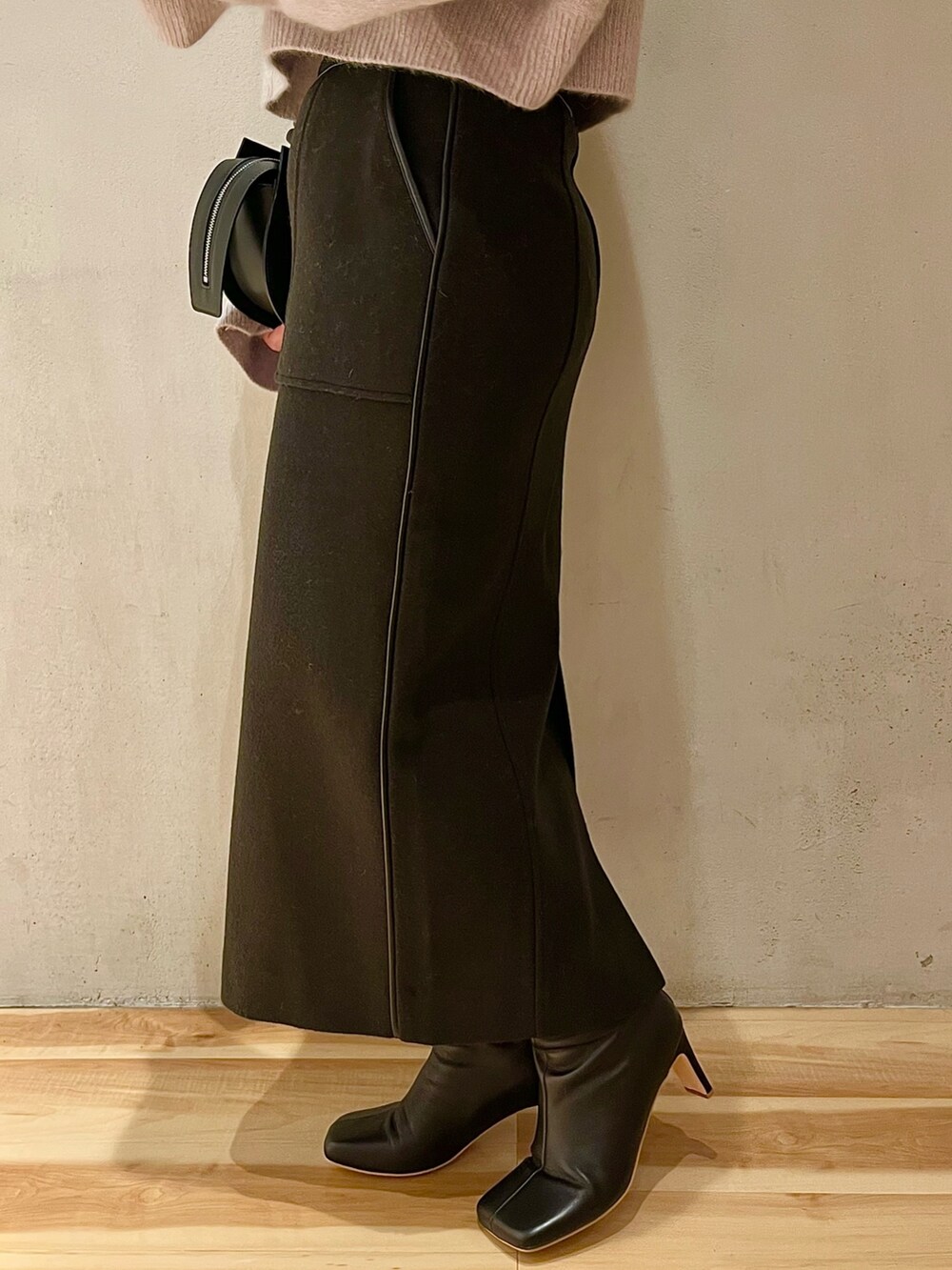 ブラック系のスカート、ブラック系のブーツ、ブラック系のハンドバッグを着用したレディースの秋コーディネートの7枚目の写真