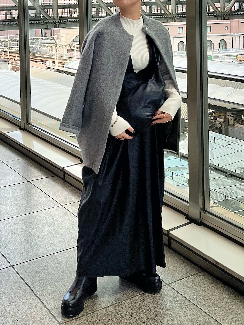 グレー系のノーカラージャケット、ブラック系のジャンパースカート、ホワイト系のニット/セーターを着用したレディースの秋コーディネートの3枚目の写真