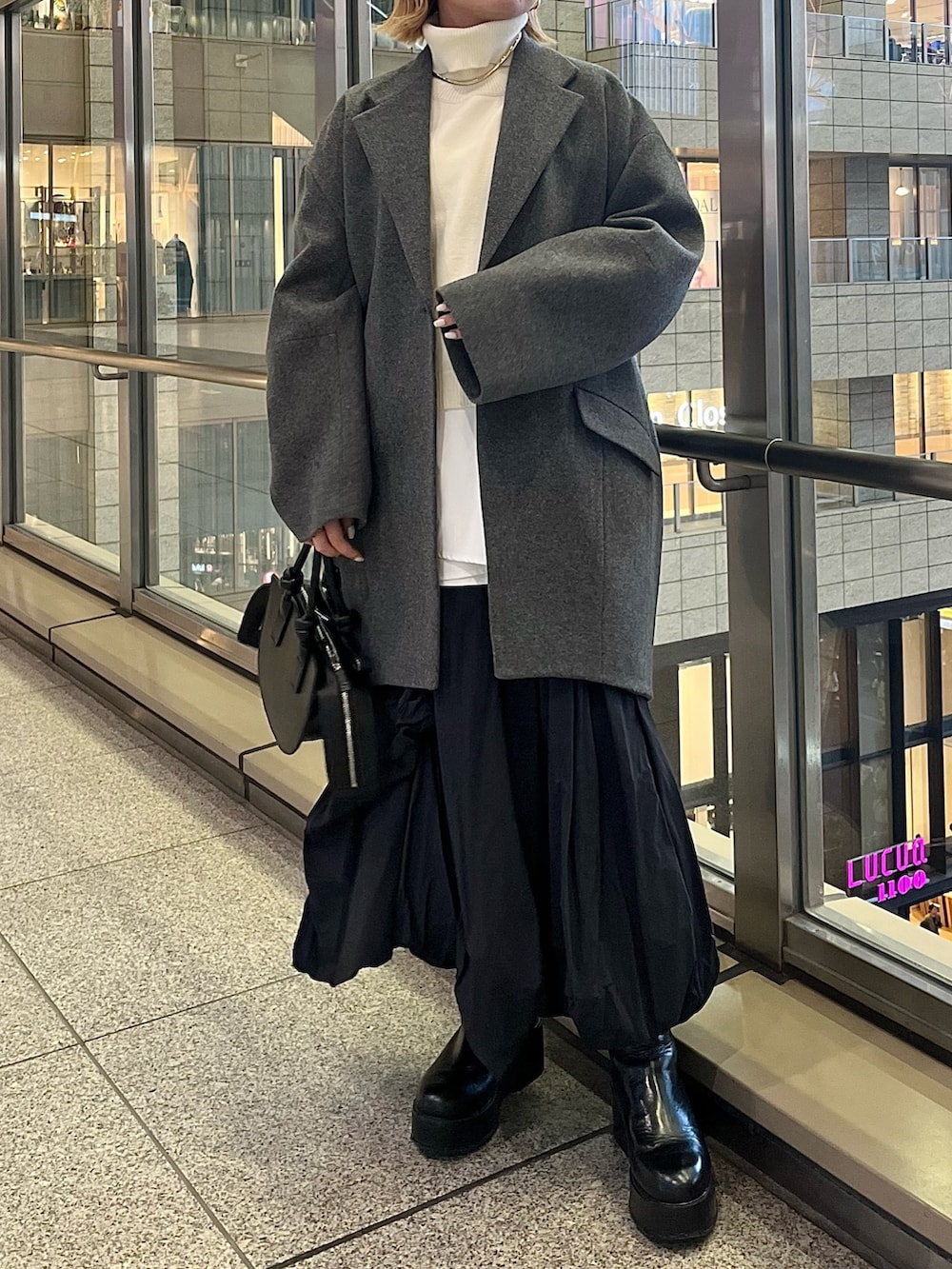 ブラック系のスカート、ブラック系のブーツ、ブラック系のハンドバッグを着用したレディースの冬コーディネートの3枚目の写真