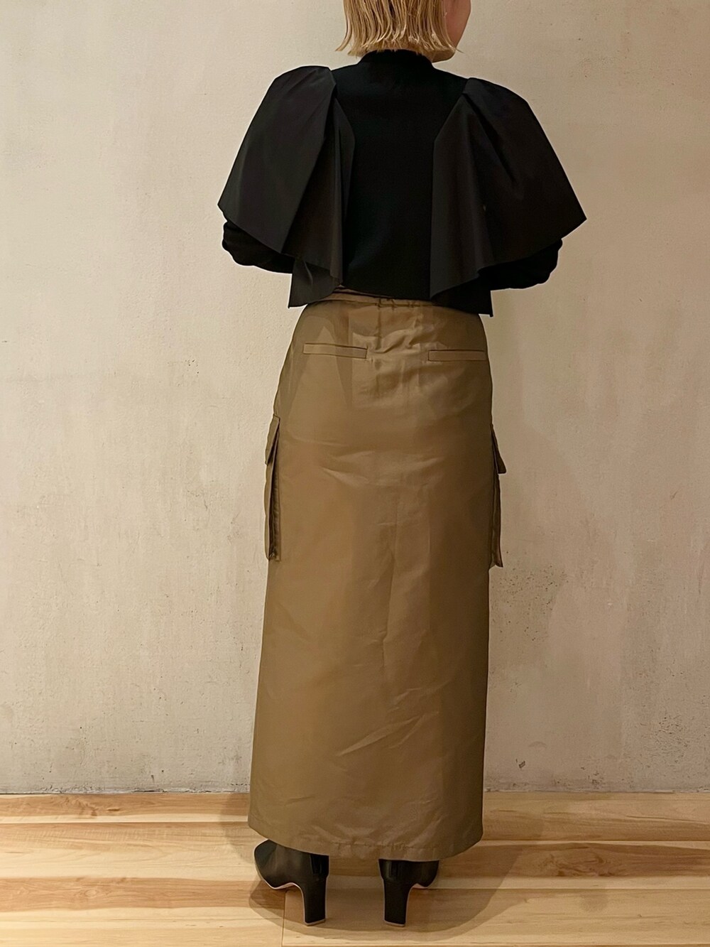 ブラウン系のスカート、ブラック系のブーツ、ブラック系のニット/セーターを着用したレディースの春コーディネートの7枚目の写真