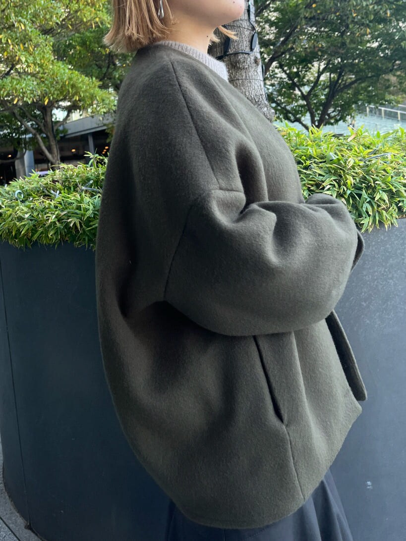 ブラック系のスカート、ブラック系のブーツ、グリーン系のノーカラーコートを着用したレディースの秋コーディネートの7枚目の写真