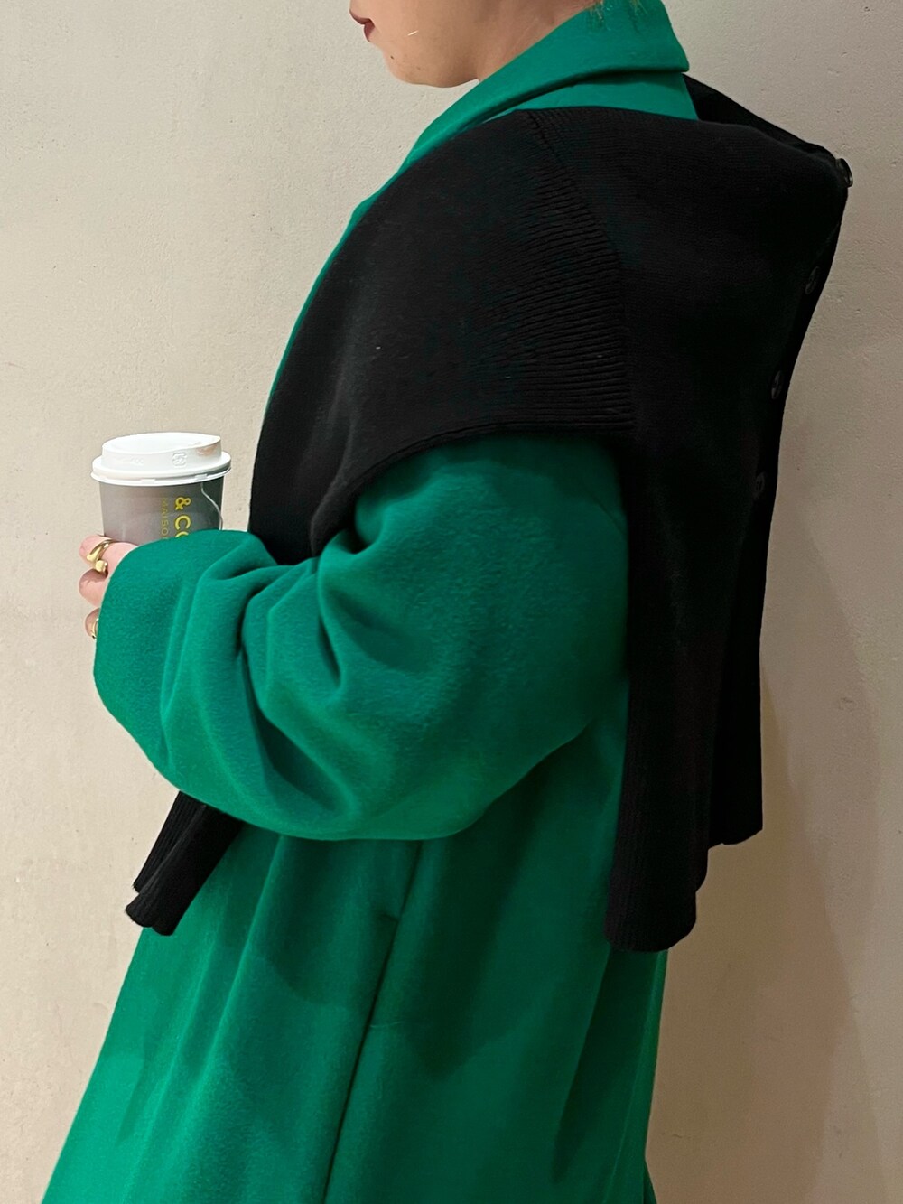 グリーン系のチェスターコート、ブラック系のカーディガン/ボレロ、ベージュ系のワンピースを着用したレディースの冬コーディネートの4枚目の写真