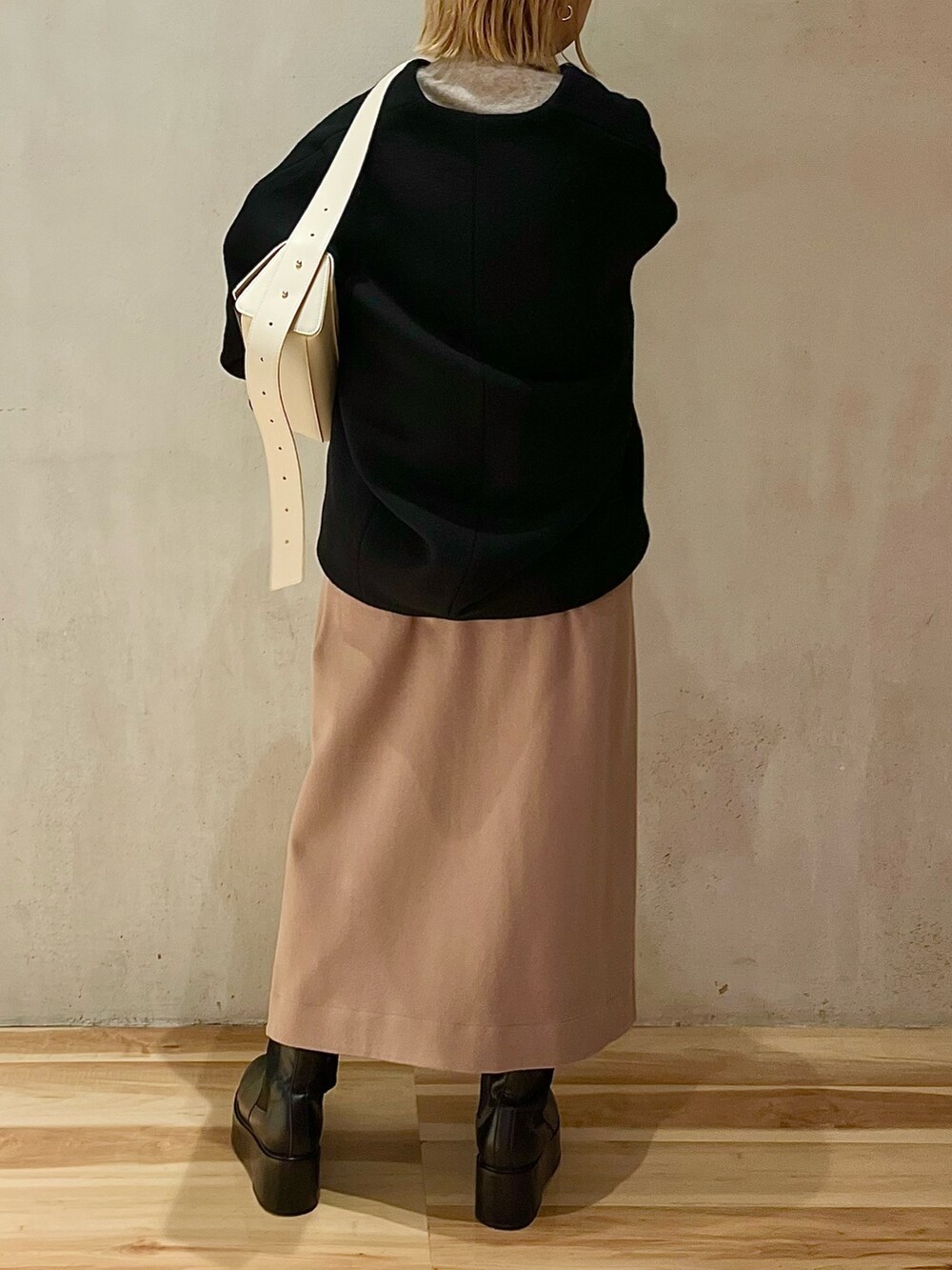 ブラック系のノーカラーコート、ベージュ系のニット/セーター、ベージュ系のスカートを着用したレディースの秋コーディネートの4枚目の写真