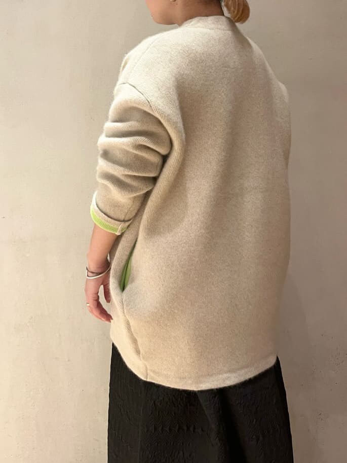 ベージュ系のショルダーバッグ、ホワイト系のカーディガン/ボレロ、ブラウン系のブーツを着用したレディースの秋コーディネートの6枚目の写真