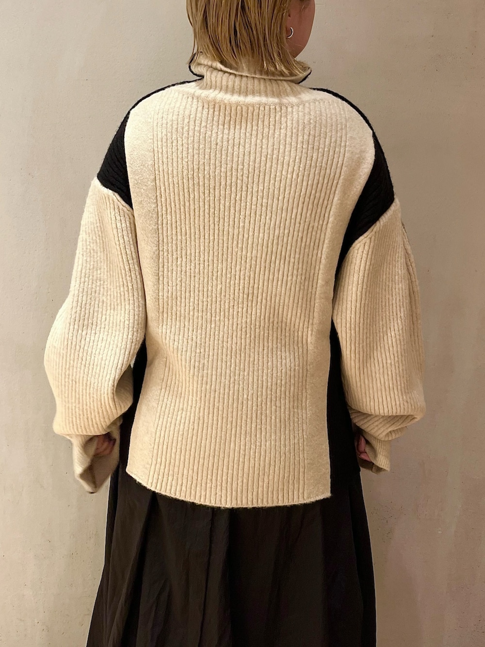 ブラック系のスカート、ホワイト系のニット/セーター、ブラック系のブーツを着用したレディースの秋コーディネートの5枚目の写真