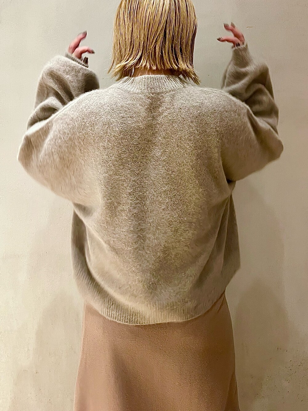 ベージュ系のニット/セーター、ベージュ系のスカート、ブラック系のブーツを着用したレディースの秋コーディネートの6枚目の写真