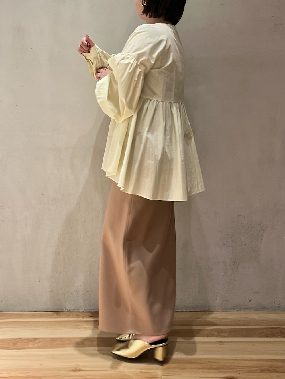 イエロー系のシャツ/ブラウス、ベージュ系のスカート、ゴールド系のパンプスを着用したレディースの春コーディネートの2枚目の写真