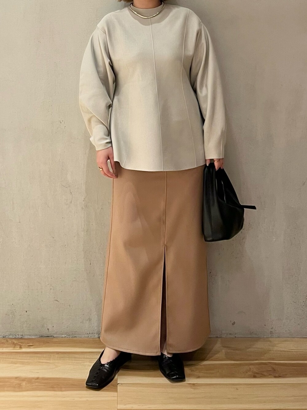 グレー系のニット/セーター、ベージュ系のスカートを着用したレディースの冬コーディネートの2枚目の写真