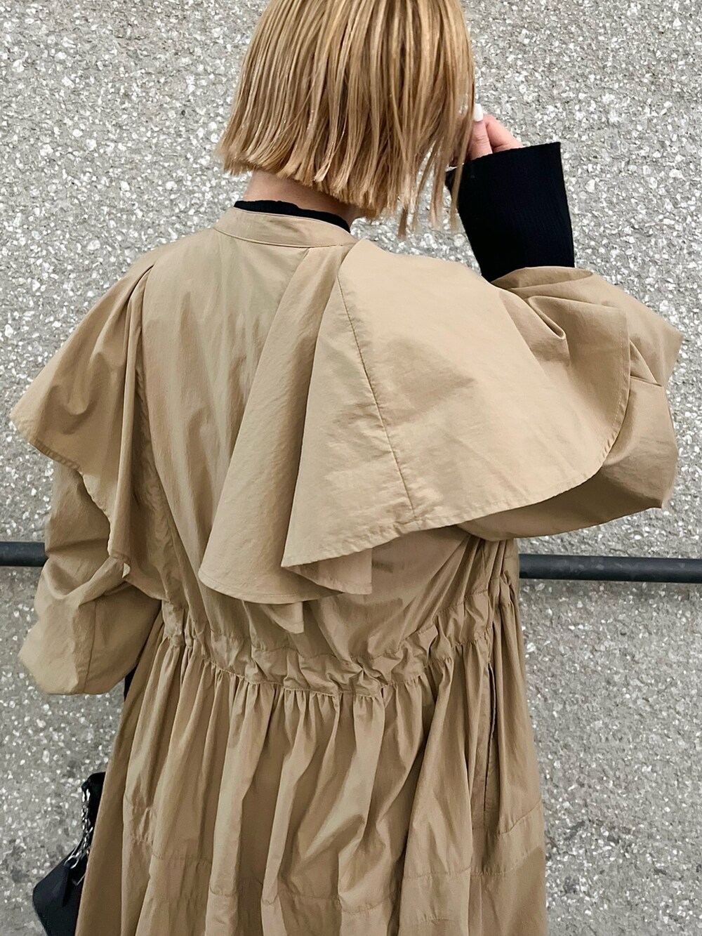 ベージュ系のトレンチコート、ブラック系のニット/セーター、ホワイト系のその他パンツを着用したレディースの春コーディネートの5枚目の写真