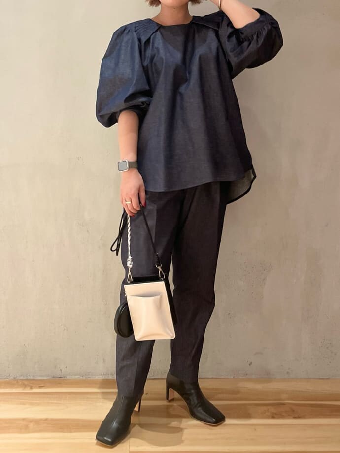 ホワイト系のショルダーバッグ、イエロー系のカーディガン/ボレロ、ブラック系のブーツを着用したレディースの秋コーディネートの5枚目の写真