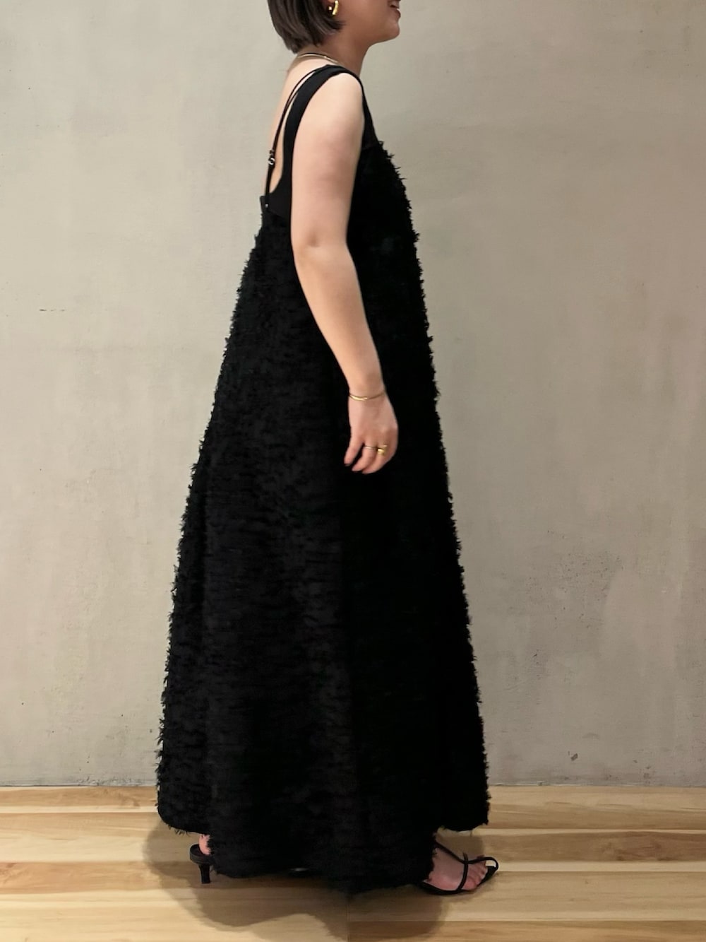 ブラック系のワンピース、ブラック系のタンクトップ、ベージュ系のノーカラーコートを着用したレディースの春コーディネートの8枚目の写真