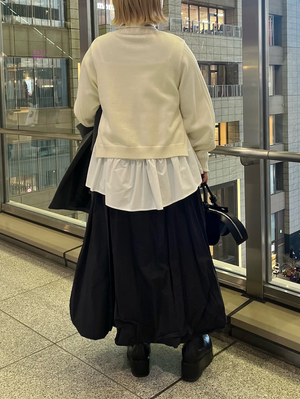 ブラック系のスカート、ブラック系のブーツ、ブラック系のハンドバッグを着用したレディースの冬コーディネートの7枚目の写真