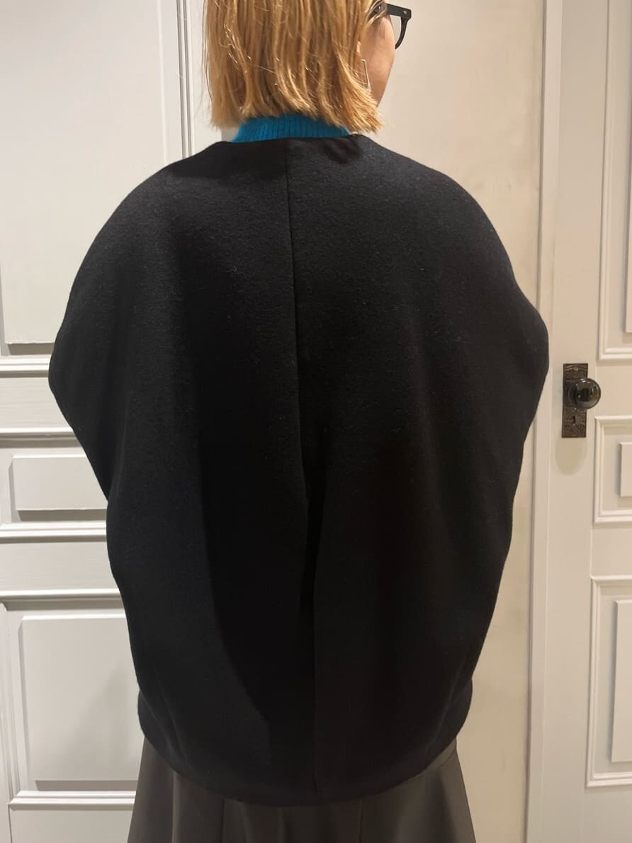 ブラック系のスカート、ブラック系のノーカラーコート、ブルー系のニット/セーターを着用したレディースの秋コーディネートの7枚目の写真