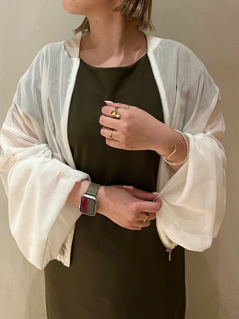 ホワイト系のサンダル、ホワイト系のブルゾン、グリーン系のワンピースを着用したレディースの冬コーディネートの4枚目の写真