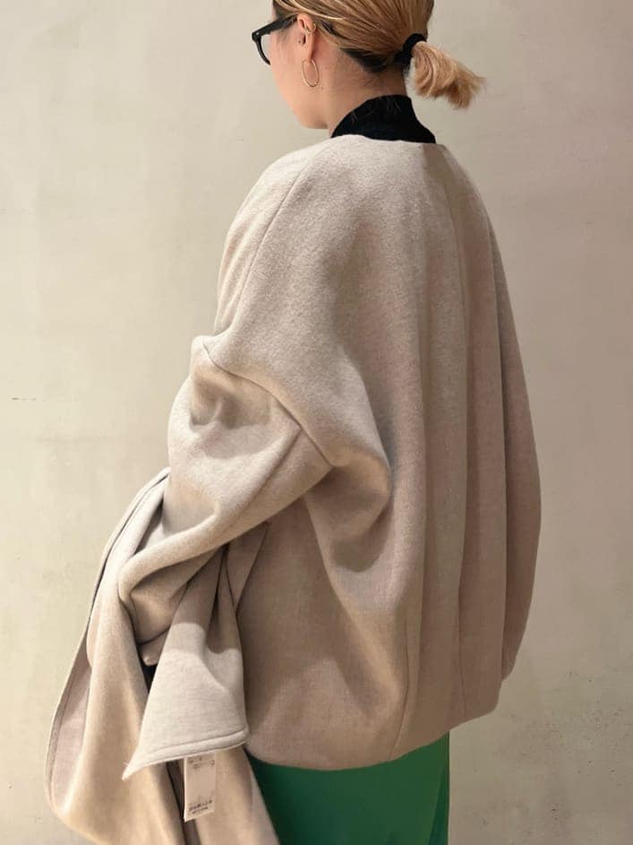 グリーン系のスカート、ベージュ系のノーカラーコート、ブラック系のニット/セーターを着用したレディースの秋コーディネートの7枚目の写真