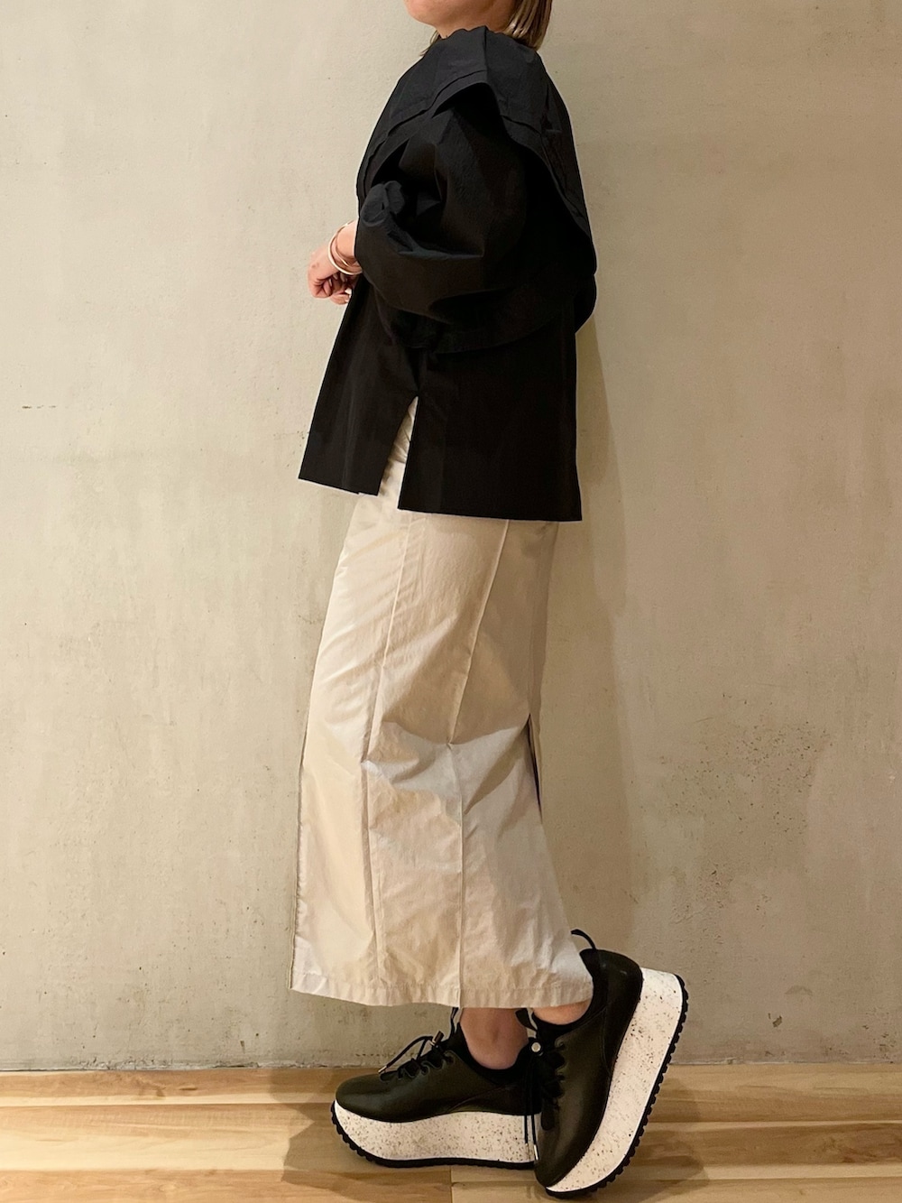 ブラック系のスニーカー、ブラック系のシャツ/ブラウス、ベージュ系のスカートを着用したレディースの冬コーディネートの2枚目の写真