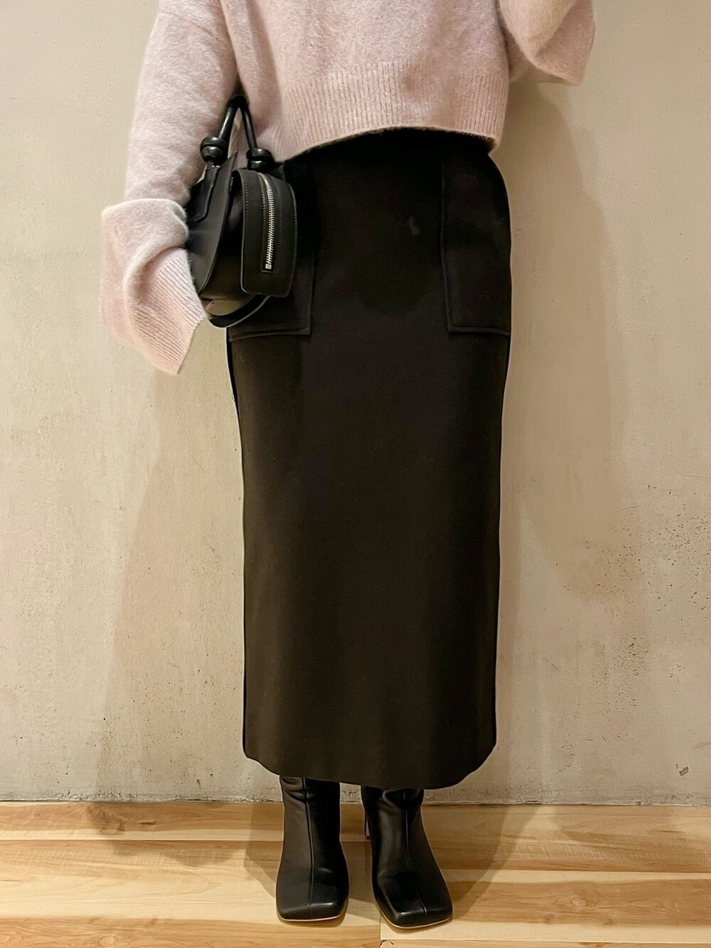 ブラック系のスカート、ブラック系のブーツ、ブラック系のハンドバッグを着用したレディースの秋コーディネートの6枚目の写真