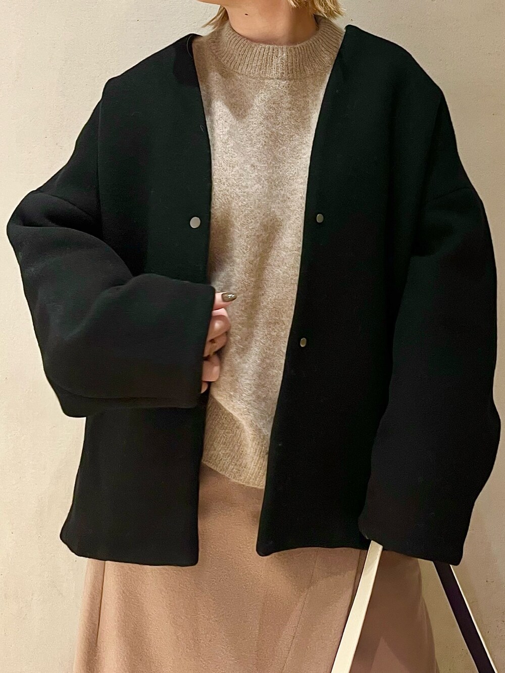 ブラック系のノーカラーコート、ベージュ系のニット/セーター、ベージュ系のスカートを着用したレディースの秋コーディネートの5枚目の写真