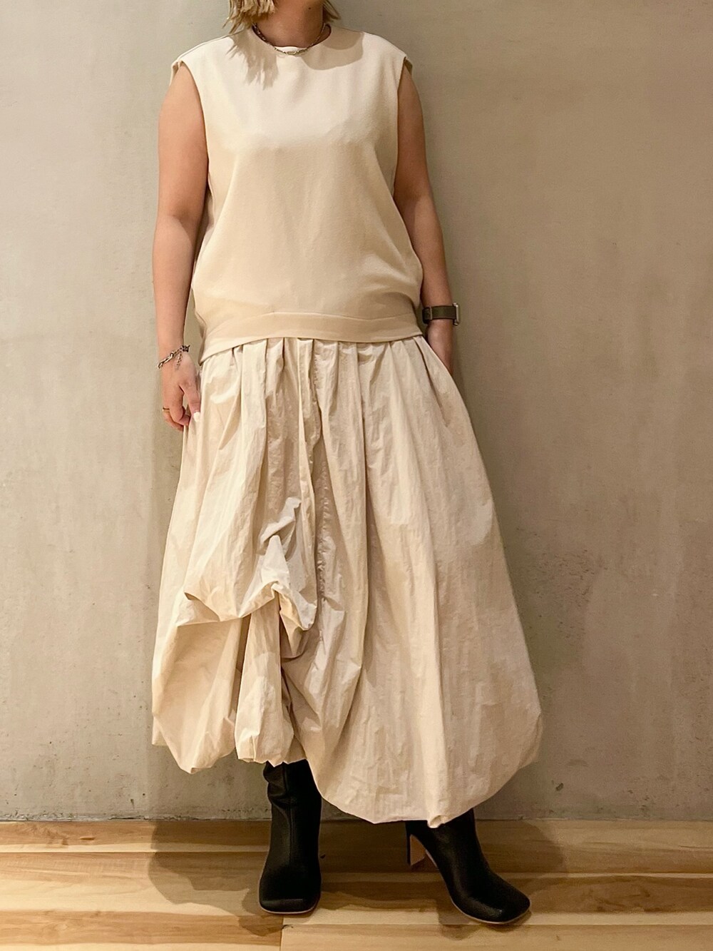 ベージュ系のノーカラージャケット、ベージュ系のワンピース、ブラック系のブーツを着用したレディースの夏コーディネートの5枚目の写真