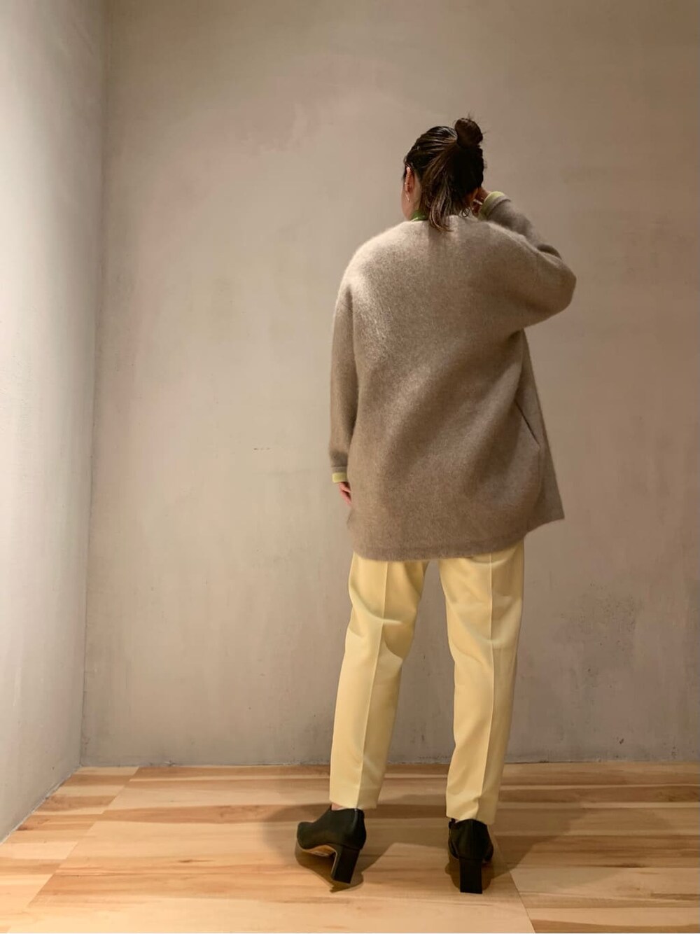 ブラック系のブーツ、イエロー系のスラックス、ブラウン系のカーディガン/ボレロを着用したレディースの秋コーディネートの3枚目の写真