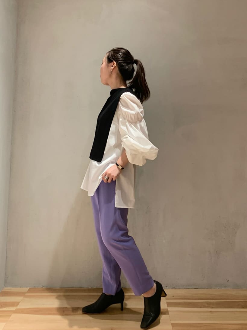 パープル系のスラックス、ホワイト系のニット/セーター、ブラック系のブーツを着用したレディースの秋コーディネートの4枚目の写真