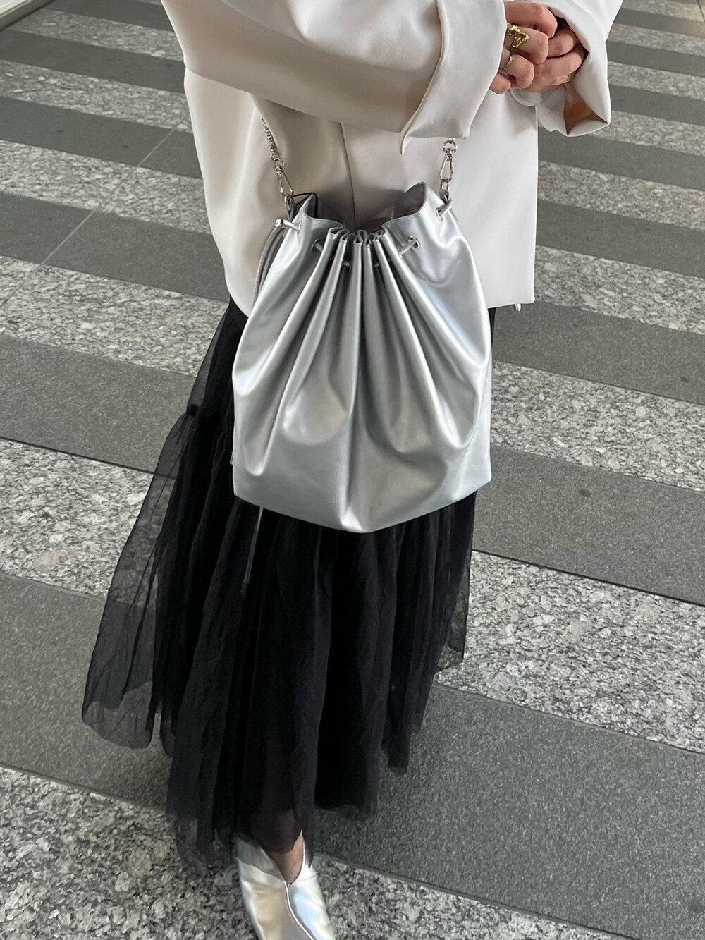 ベージュ系のノーカラーコート、ブラック系のタンクトップ、ブラック系のスカートを着用したレディースの冬コーディネートの10枚目の写真