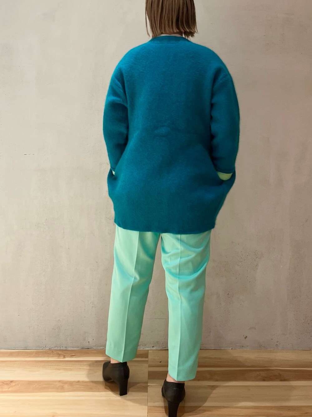 グリーン系のカーディガン/ボレロ、ホワイト系のニット/セーター、グリーン系のその他パンツを着用したレディースの冬コーディネートの3枚目の写真