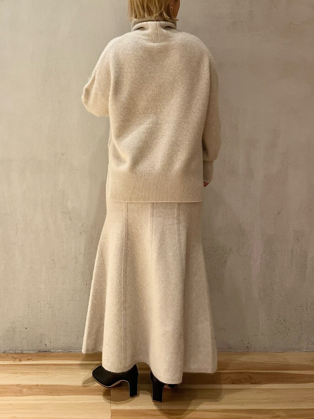 ブラック系のノーカラーコート、ホワイト系のニット/セーター、ホワイト系のスカートを着用したレディースの秋コーディネートの9枚目の写真