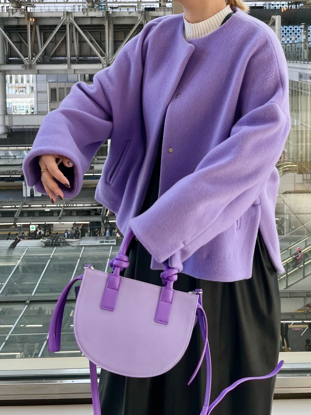 パープル系のノーカラージャケット、ブラック系のジャンパースカート、ホワイト系のニット/セーターを着用したレディースの秋コーディネートの6枚目の写真