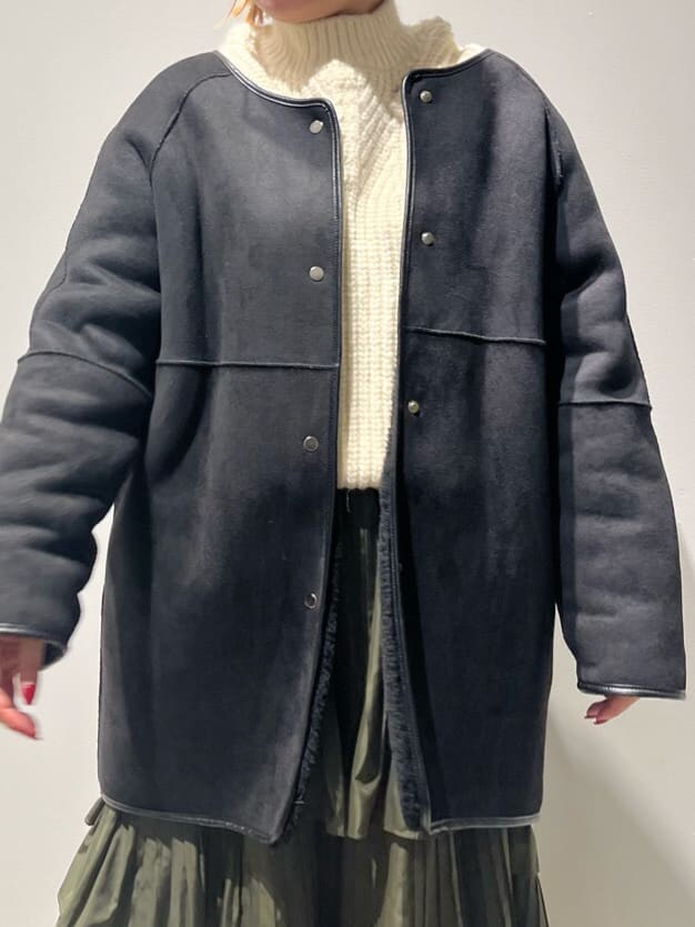 ブラック系のその他アウター、ホワイト系のニット/セーター、グリーン系のスカートを着用したレディースの秋コーディネートの6枚目の写真