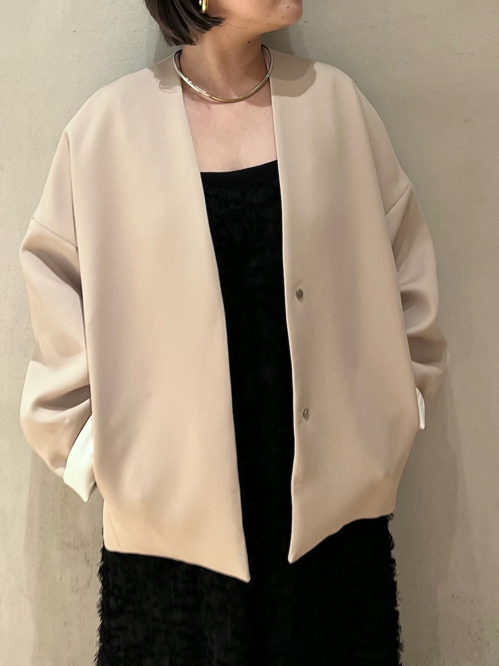 ブラック系のワンピース、ブラック系のタンクトップ、ベージュ系のノーカラーコートを着用したレディースの春コーディネートの5枚目の写真