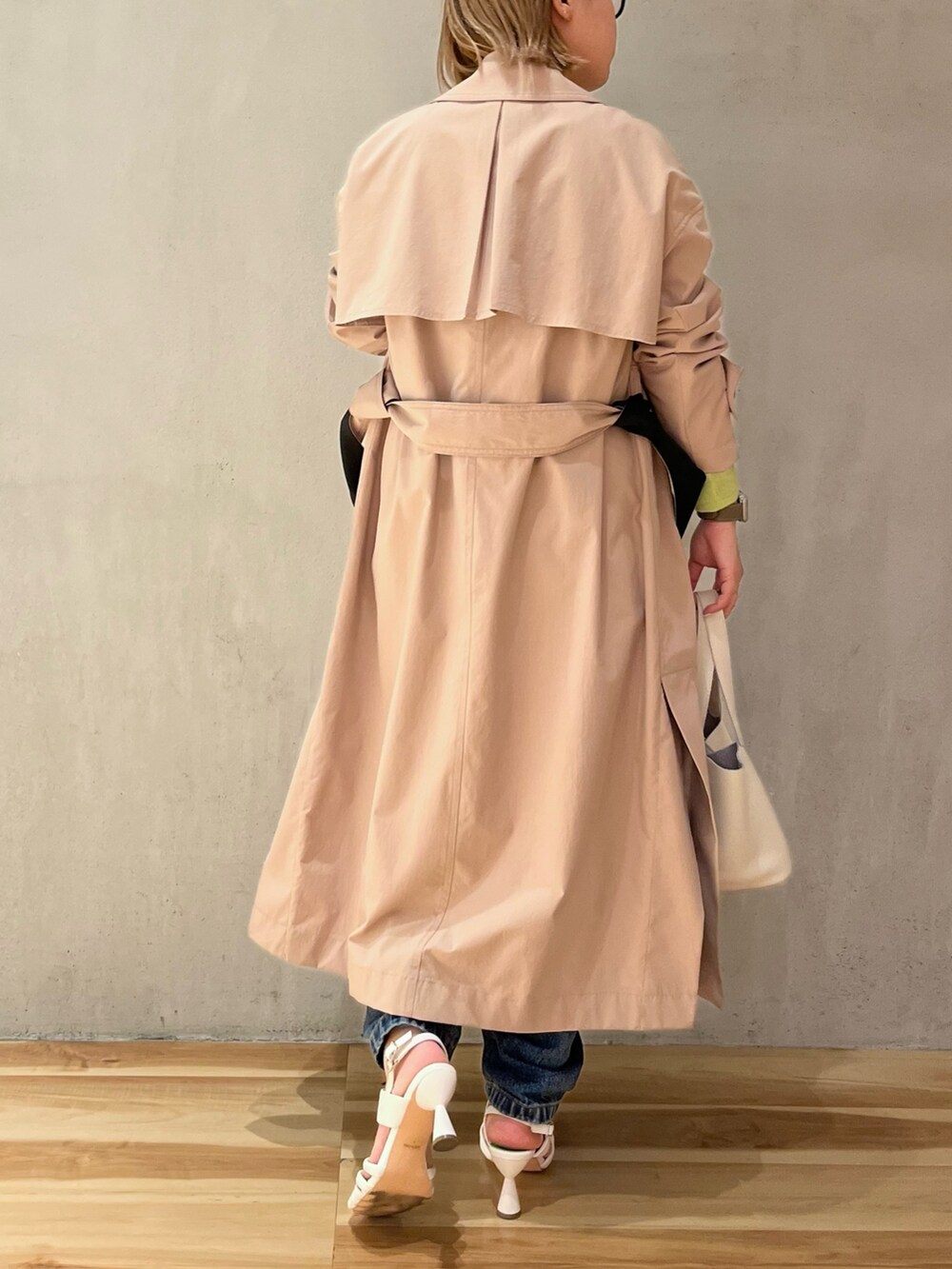 グリーン系のニット/セーター、ベージュ系のトレンチコート、ブルー系のデニムパンツを着用したレディースの冬コーディネートの3枚目の写真