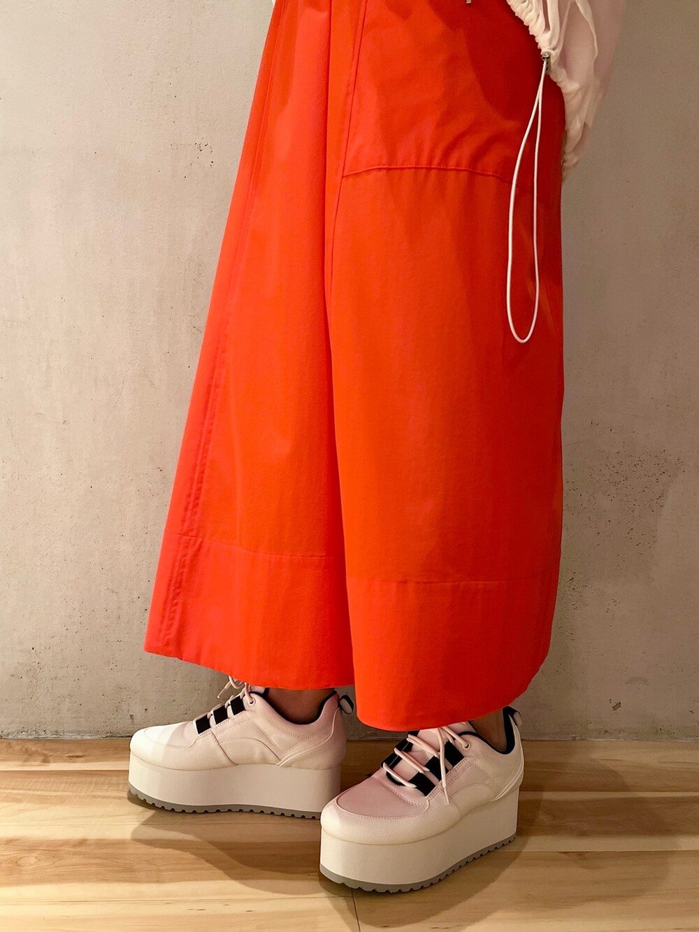 ホワイト系のブルゾン、レッド系のワンピース、ホワイト系のスニーカーを着用したレディースの夏コーディネートの7枚目の写真