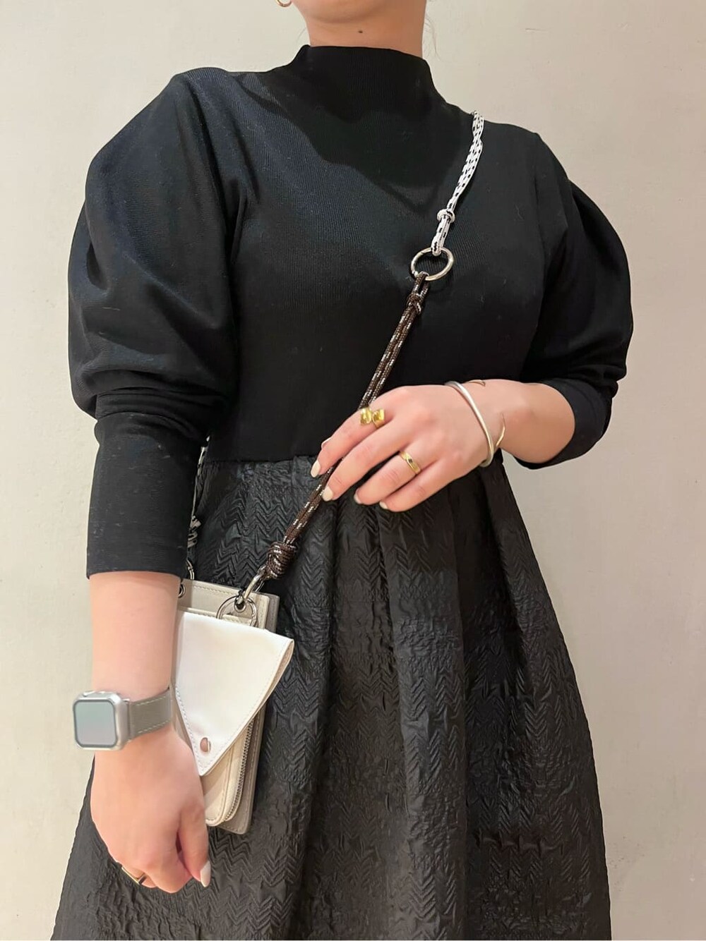 ベージュ系のショルダーバッグ、ブラウン系のブーツ、ブラック系のワンピースを着用したレディースの秋コーディネートの5枚目の写真