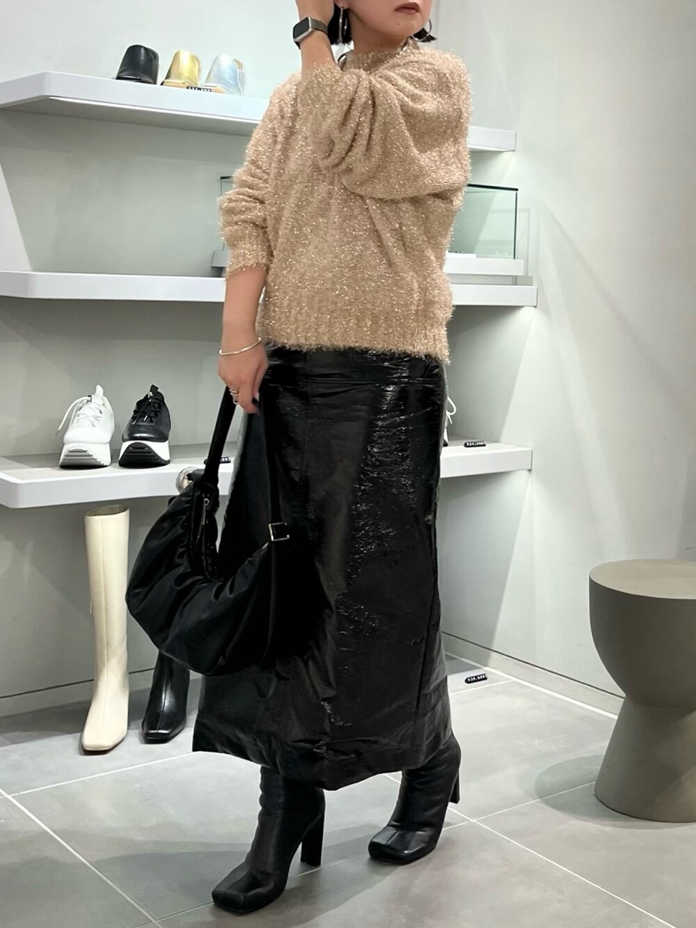 ベージュ系のニット/セーター、ブラック系のブーツ、ブラック系のハンドバッグを着用したレディースの秋コーディネートの2枚目の写真