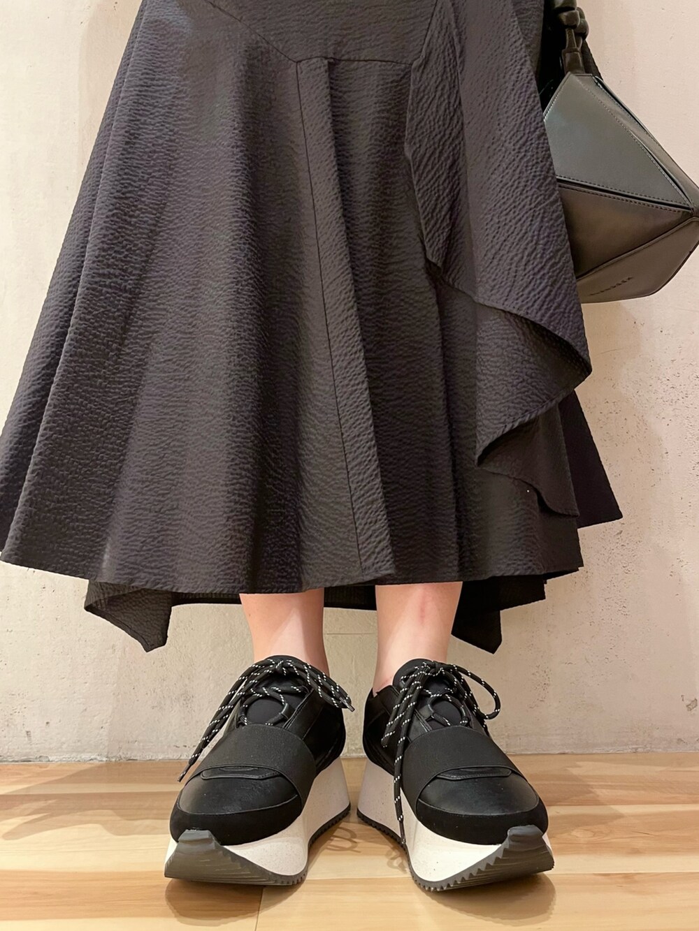 ブラック系のTシャツ/カットソー、ブラック系のスカート、ブラック系のハンドバッグを着用したレディースの春コーディネートの8枚目の写真