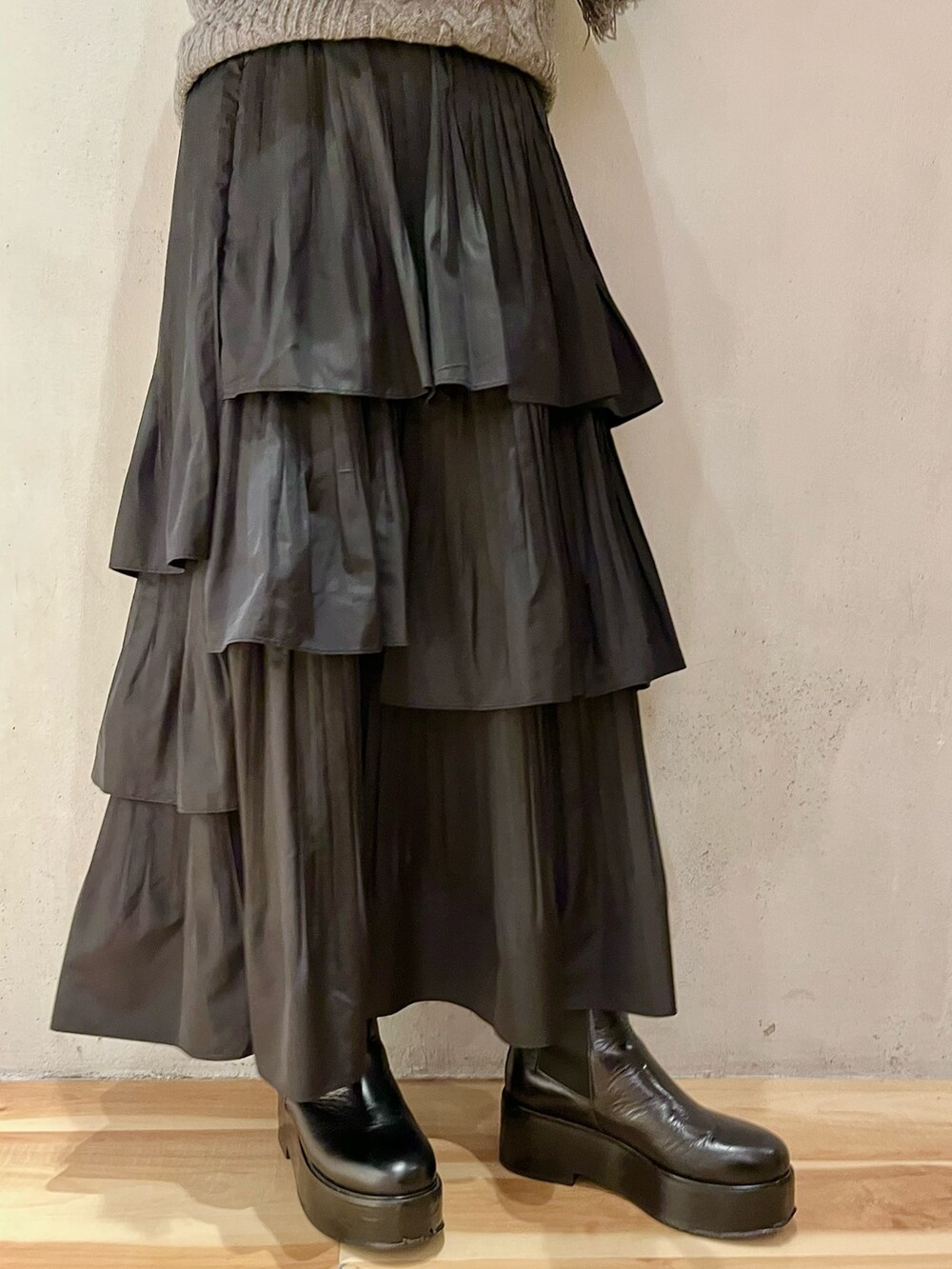 グレー系のニット/セーター、ブラック系のスカート、ブラック系のブーツを着用したレディースの秋コーディネートの7枚目の写真