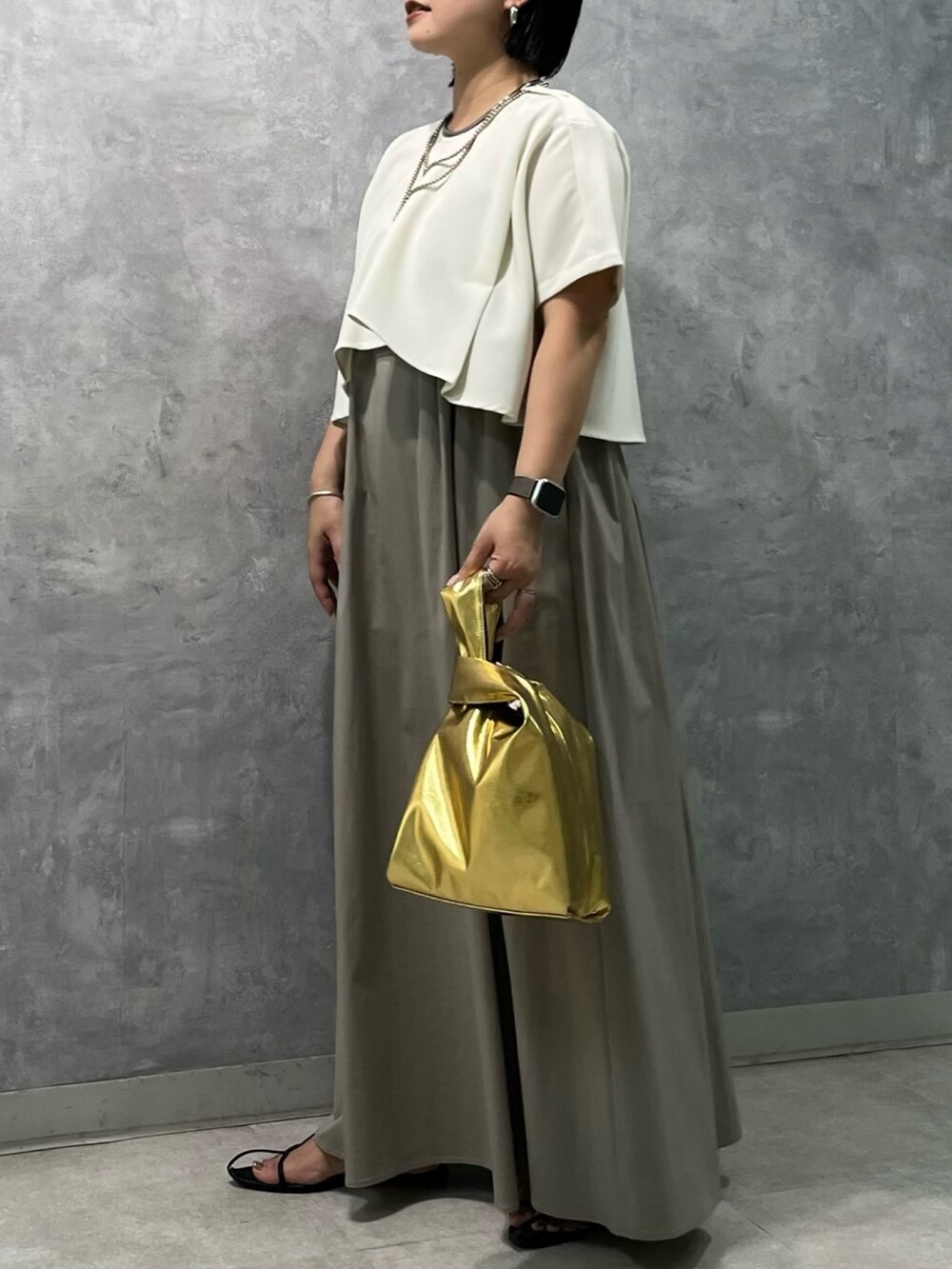 ベージュ系のワンピース、ゴールド系のハンドバッグを着用したレディースの夏コーディネートの2枚目の写真